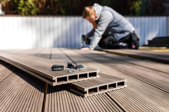 Une équipe douvriers installant une terrasse en bois composite sur une structure robuste, avec des outils de précision et un souci du détail pour une finition parfaite.